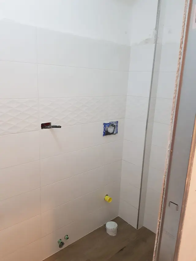 Baie cu faianță albă și racorduri pentru obiectele sanitare