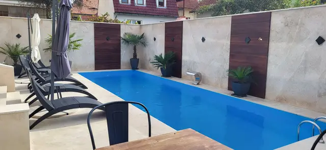 Piscină cu plajă și pereți placați cu piatră